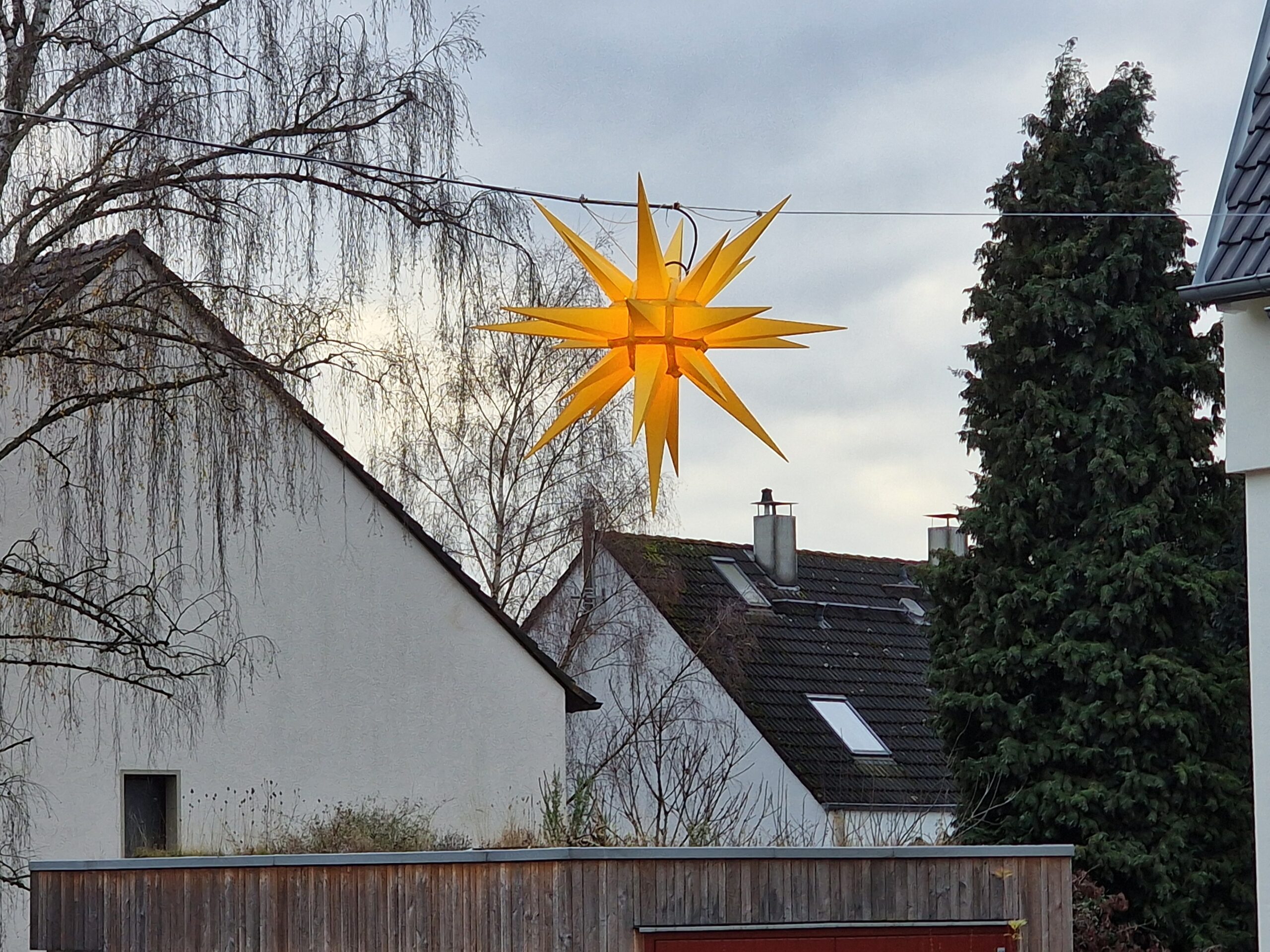 Ein Herrnhuter Stern leuchtet Am Siepen in Altenbochum vor dem Unicornflowers Garten, darunter ist die Garage mit Dachbegrünung zu sehen